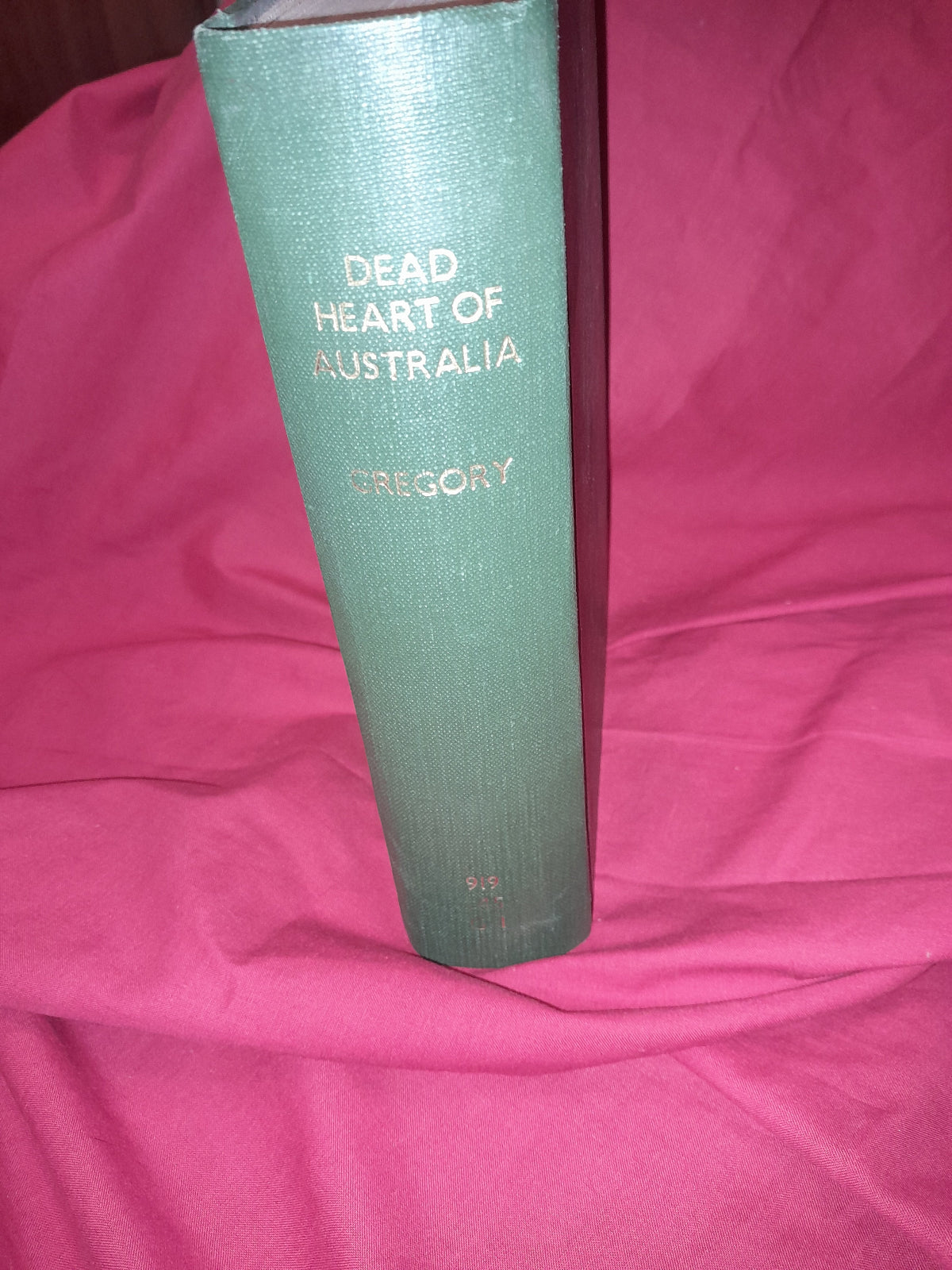 Green book titled 'Dead of Heart of Australia' on a pink fabric background
