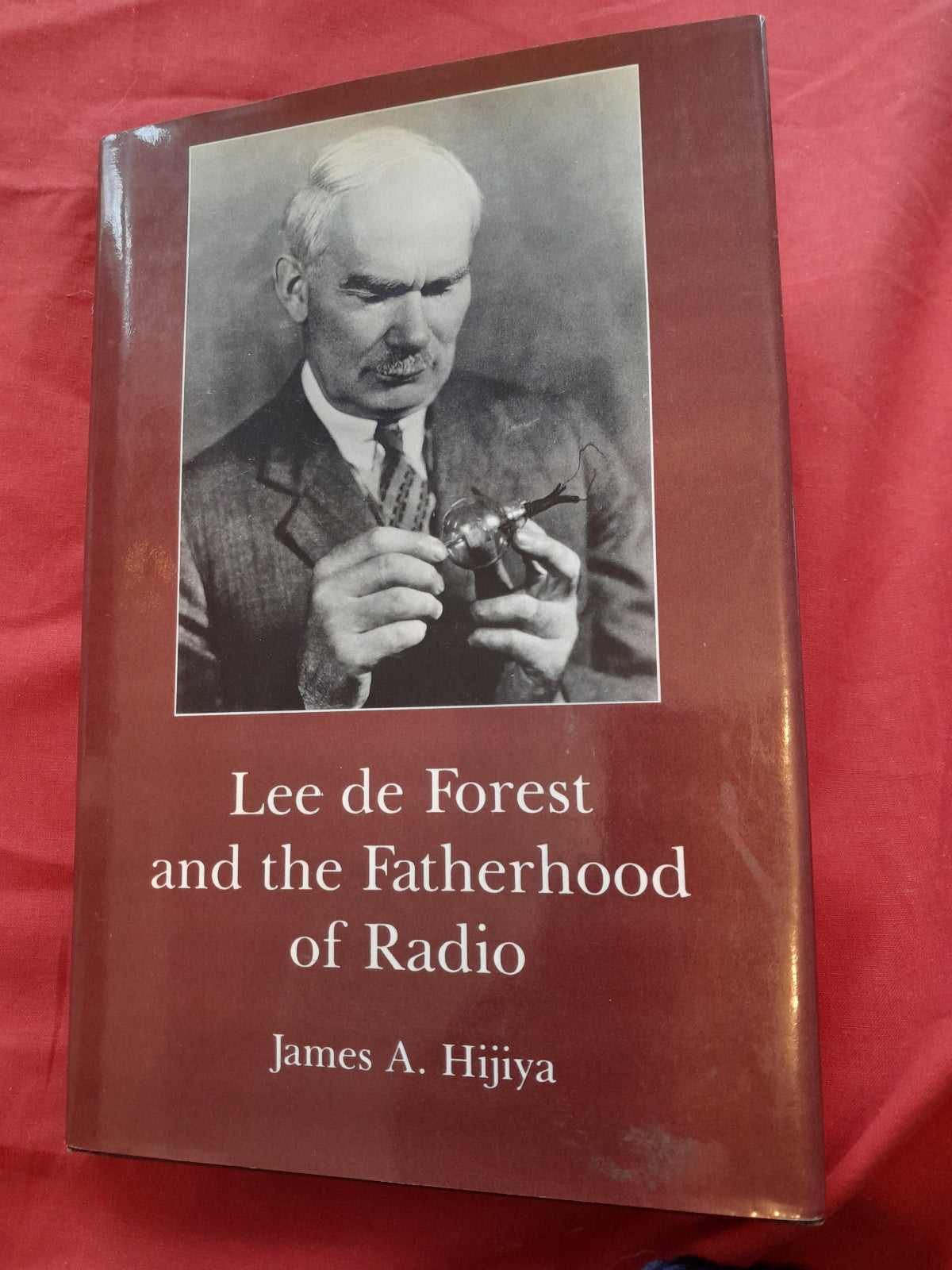 Book cover of 'Lee de Forest and the Fatherhood of Radio' with a black and white photo of a man on a red background.