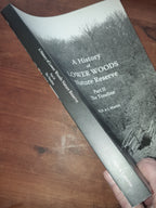 Book titled 'A History of Lower Woods Nature Reserve' held on a wooden surface