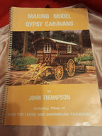 A spiral-bound book titled 'Making Model Gypsy Caravans' by John Thompson, featuring a vintage caravan illustration on the cover, photographed on a light fabric surface.
