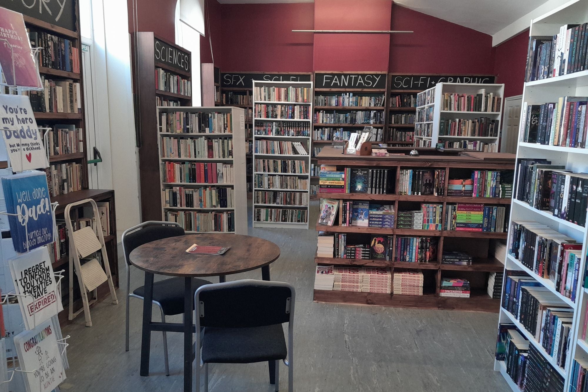 Bookstore interior with bookshelves, a table, and chairs.